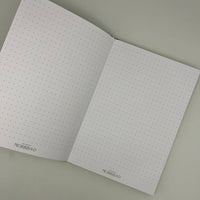 Open notebook with dot grid pages on a plain background