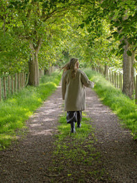 Person walking down a tree-lined path in a serene natural setting