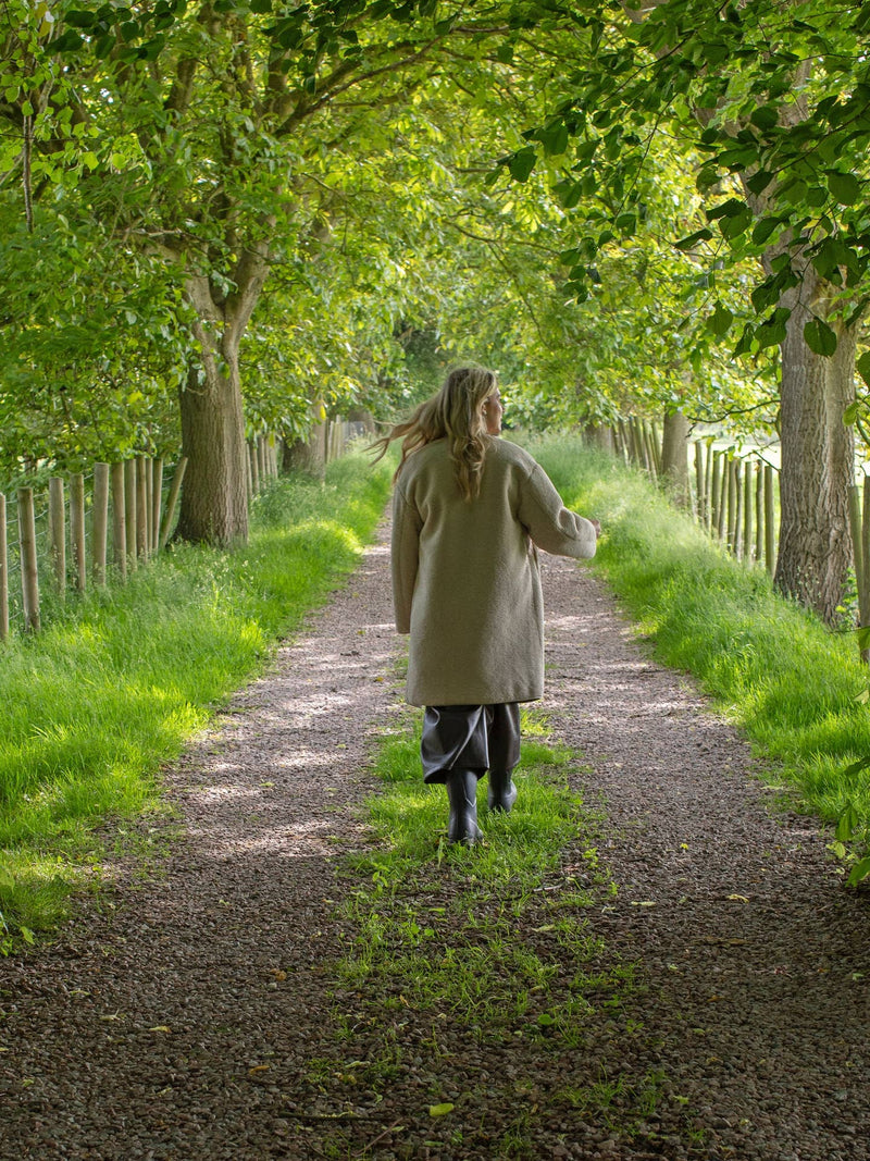 Person walking down a tree-lined path in a serene natural setting