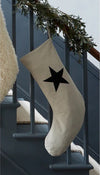 Beige Christmas stocking with a black star hanging on a staircase.