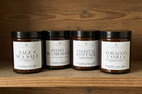 Four candle jars with labels on a neutral background