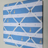 Memo board with blue and white pattern featuring small rabbits and trees on a gray wall.