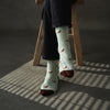 Person wearing light blue socks with red bird pattern on a wooden stool.