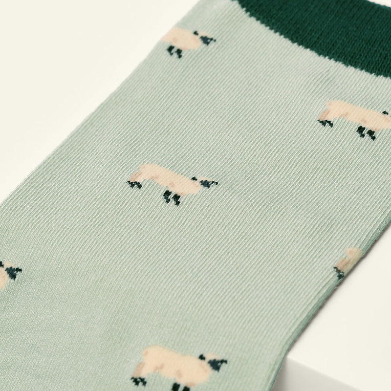 Green sock with sheep pattern on a white background