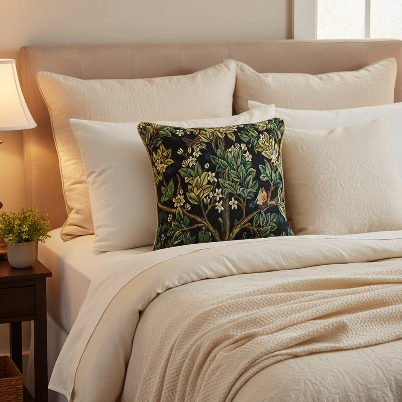Decorative pillow with nature-themed pattern featuring leaves, flowers, and birds on a black background.