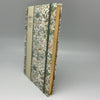 Floral-patterned notebook with a green spine on a gray background