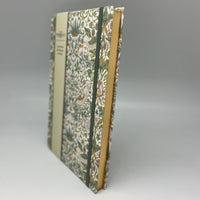 Floral-patterned notebook with a green spine on a gray background