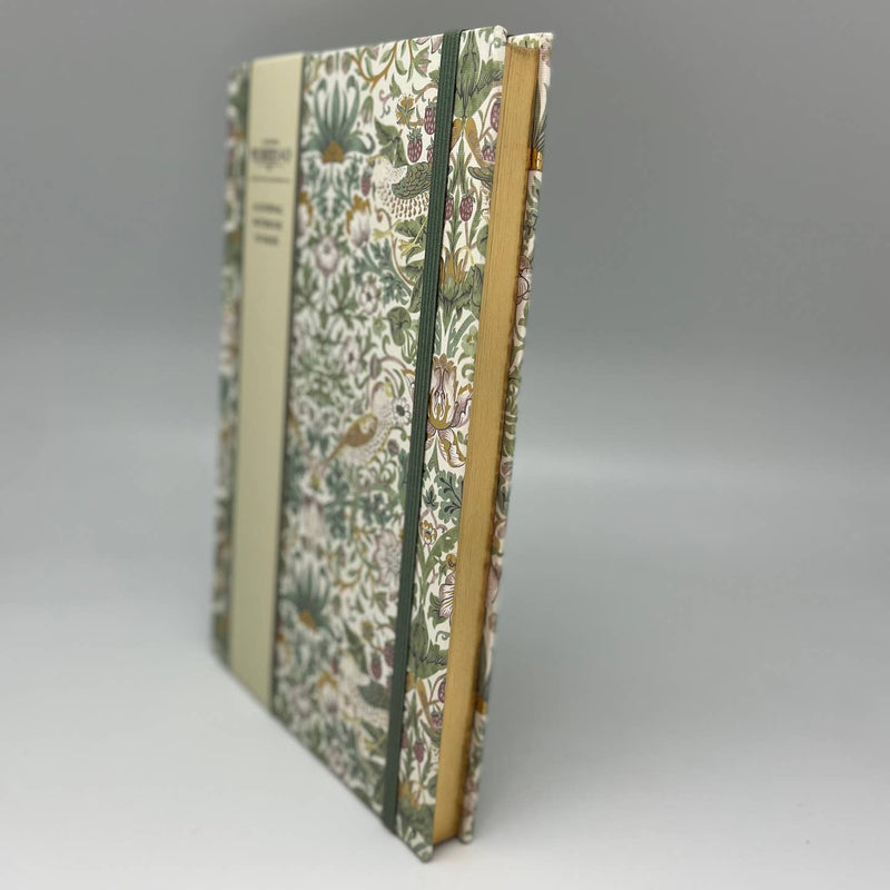 Floral-patterned notebook with a green spine on a gray background