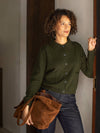 Woman in a green shirt holding a brown bag indoors.