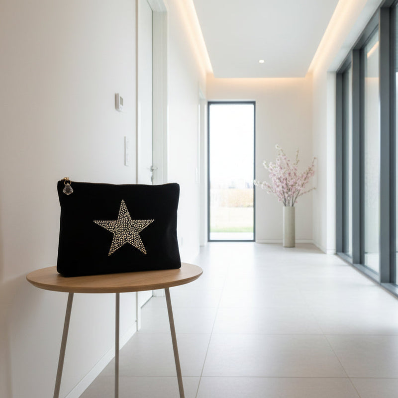 Black make up bag with a star design on a wooden stool in a modern hallway.